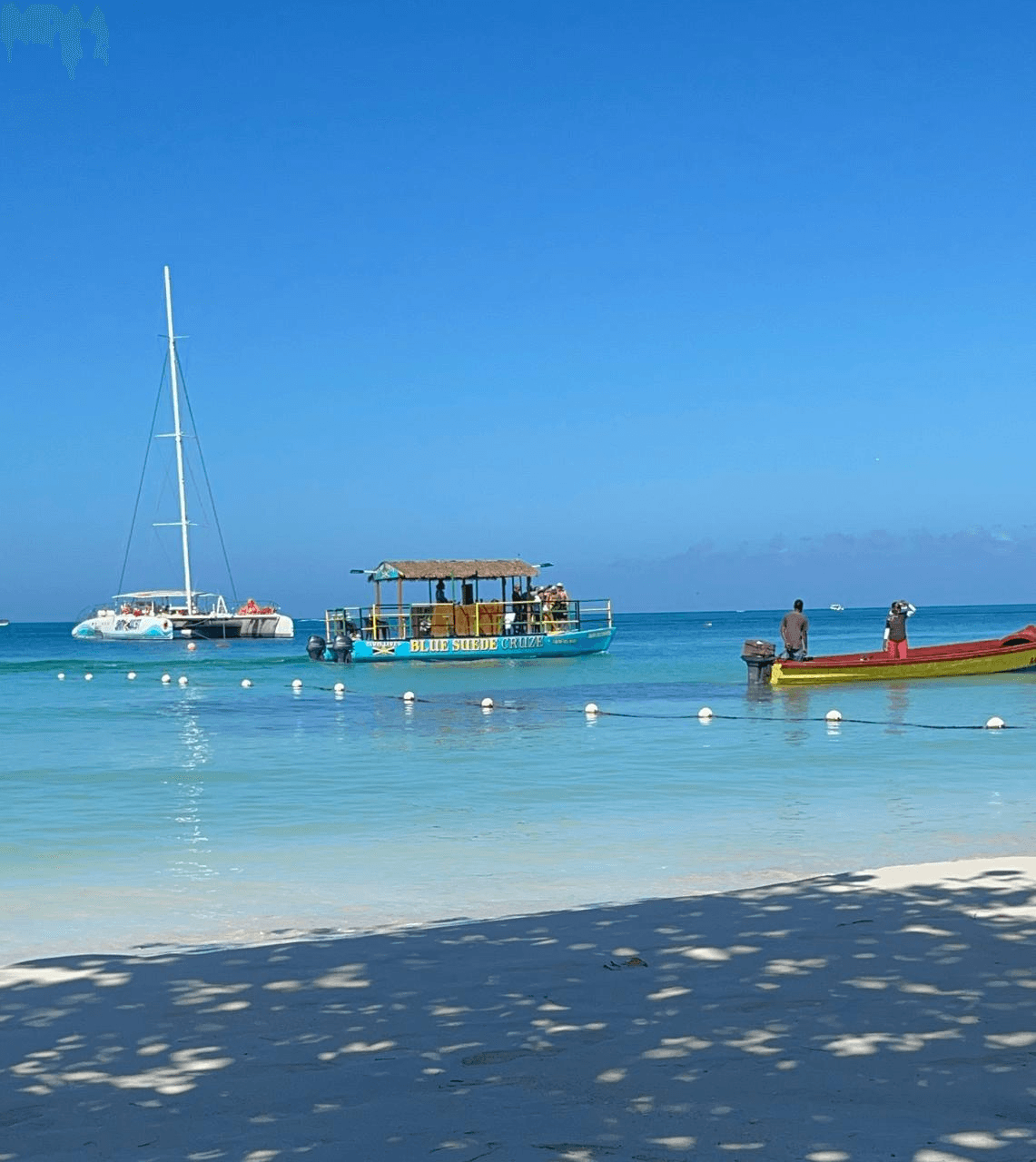 Turquoise water along a shoreline dotted with boats.