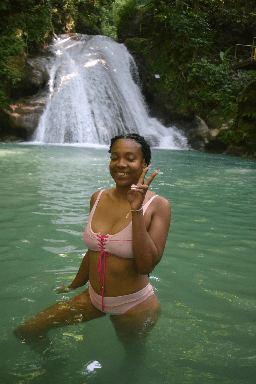 A visitor enjoying the water at the base of a waterfall.